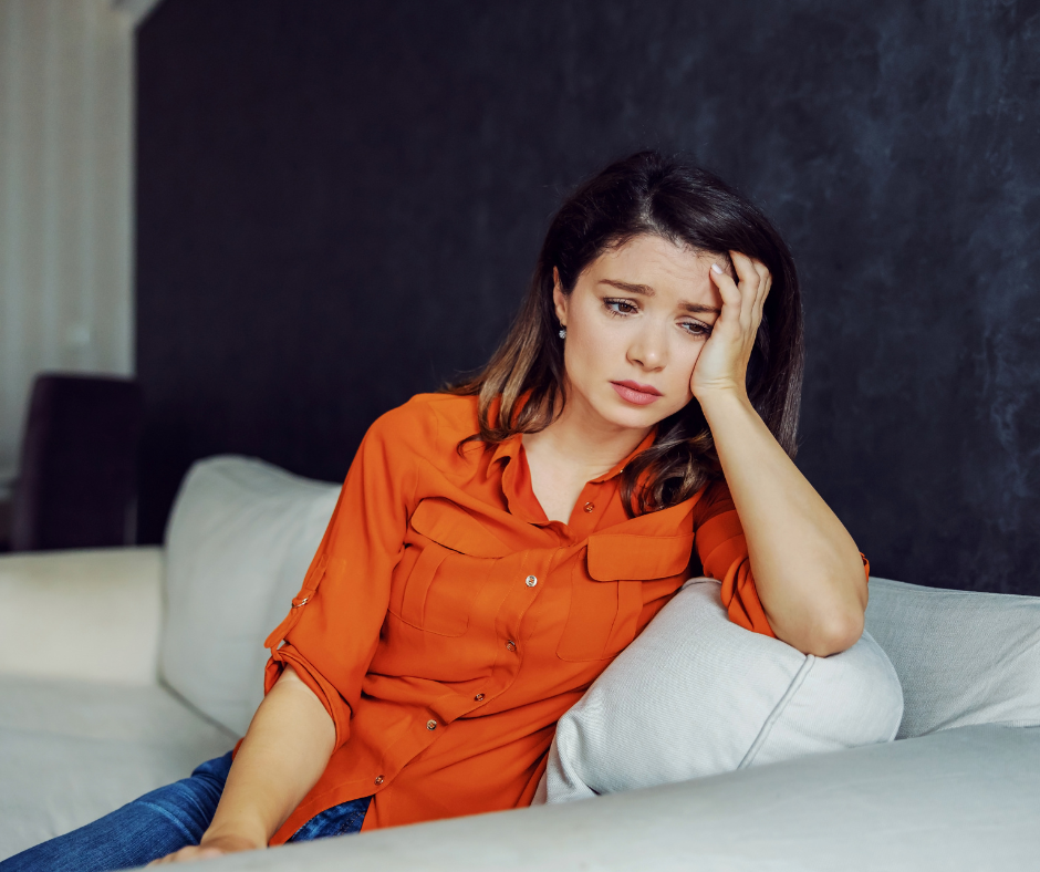 worried looking woman on sofa thinking the worst